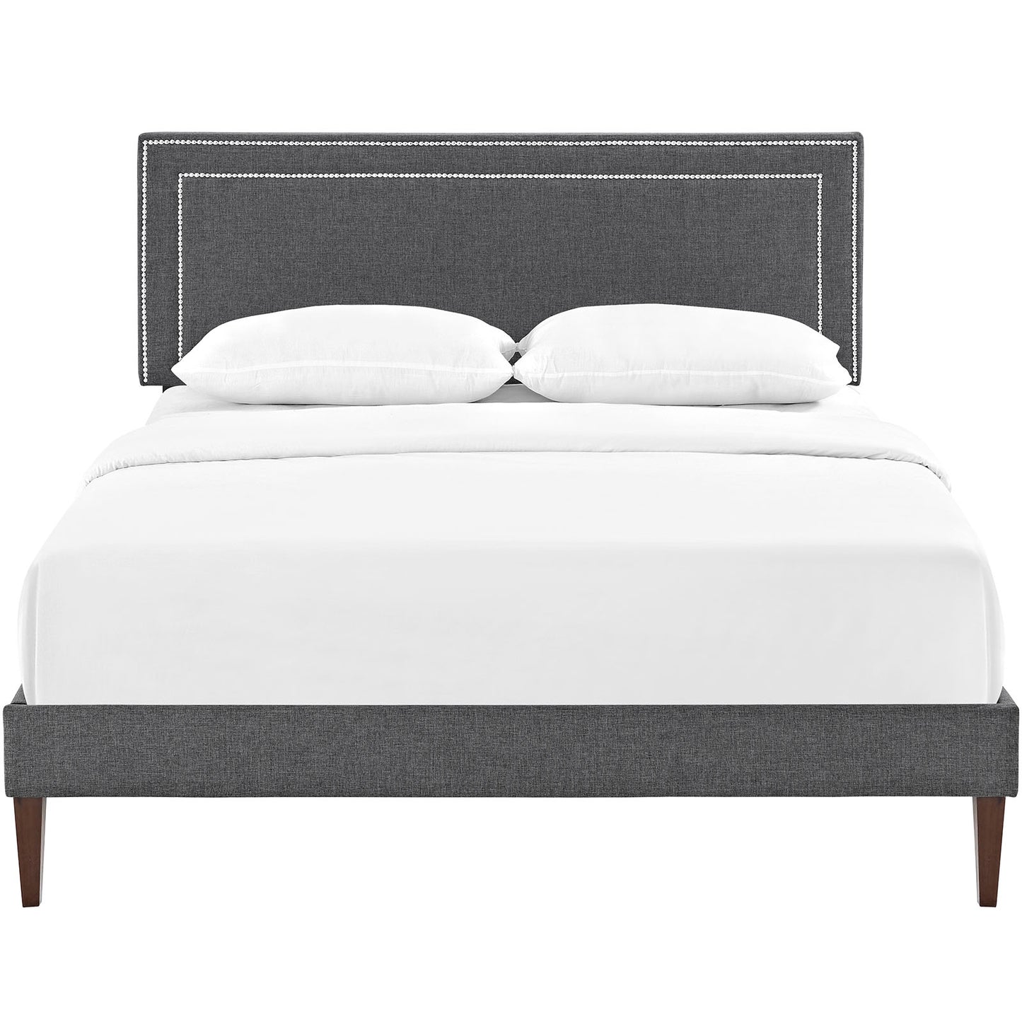 Gray upholstered platform bed with nailhead-trim headboard, white bedding, and squared tapered legs.