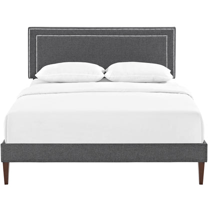 Gray upholstered platform bed with nailhead-trim headboard, white bedding, and squared tapered legs.