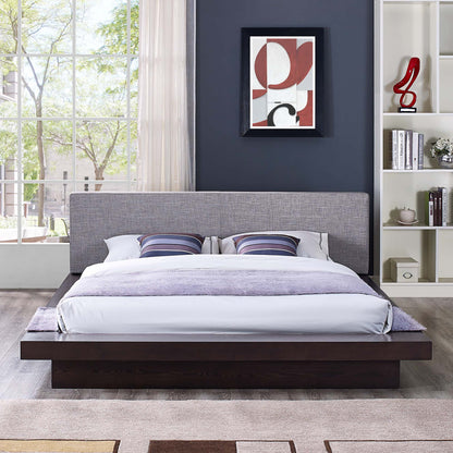 Modern gray upholstered platform bed on a dark wood base with striped pillows, blue accent wall, abstract art, and open shelves