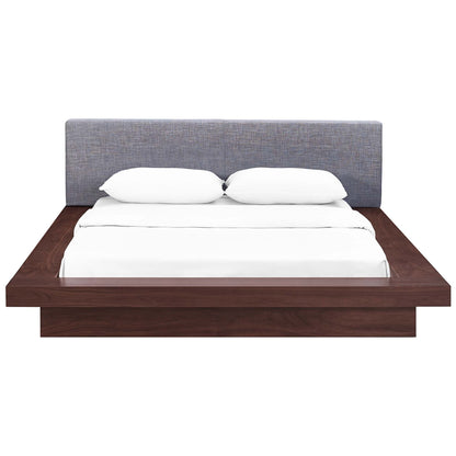 Gray fabric queen platform bed with an upholstered headboard; white bedding & two pillows; contemporary low-profile design.