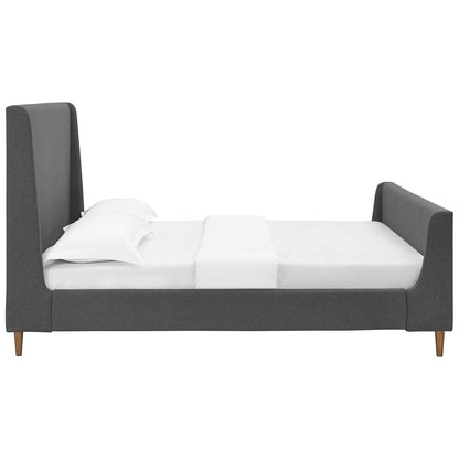 Grey upholstered fabric queen sleigh bed with white sheets and pillows