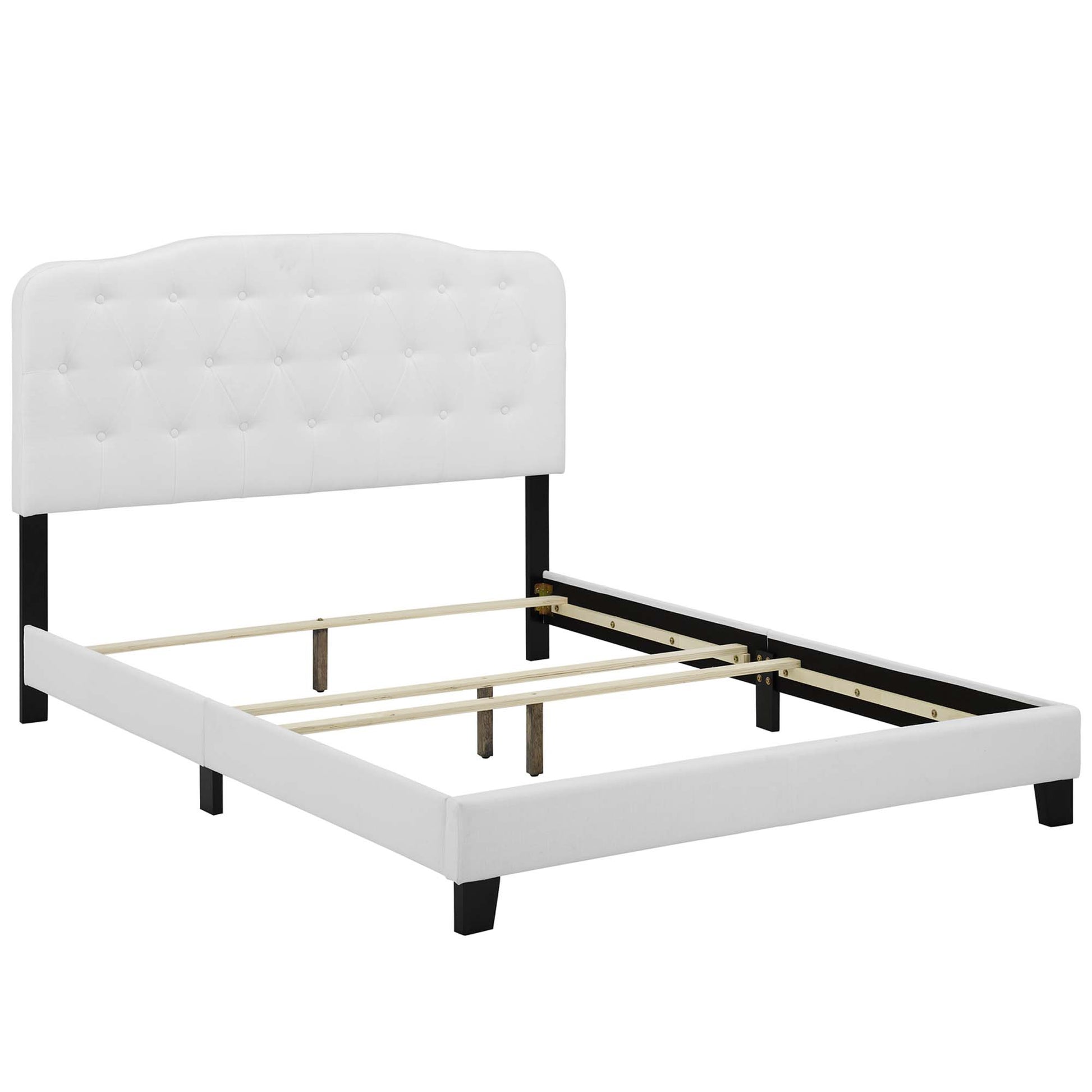 White tufted upholstered king bed with black legs and exposed wooden slat supports.