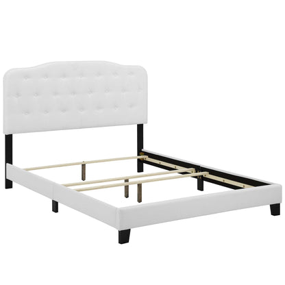 White tufted upholstered king bed with black legs and exposed wooden slat supports.