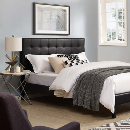 Black tufted headboard with white linens and gray throw; beige pillows, round glass side table, lamp, framed art, light blue walls.