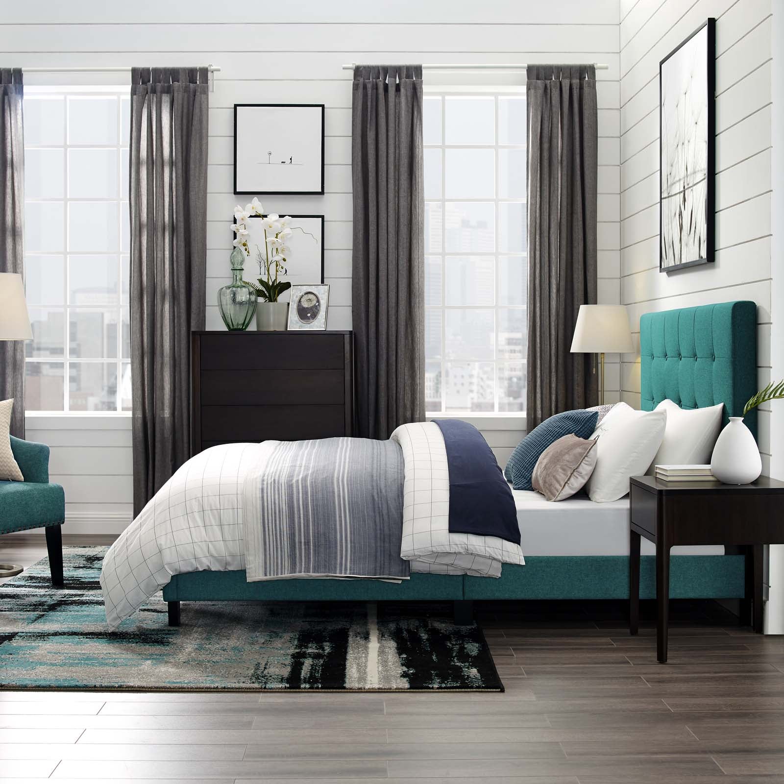 Teal upholstered bed with white and blue bedding, dark wood dresser, and gray curtains in a modern bedroom.