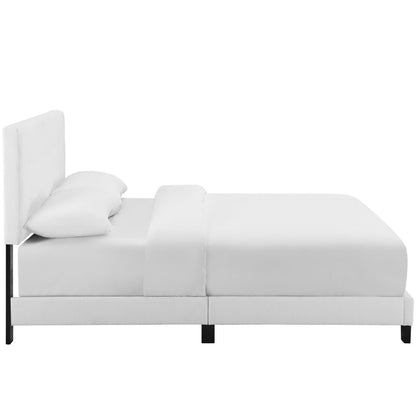 White upholstered platform bed with tall padded headboard, two pillows, and clean modern design.