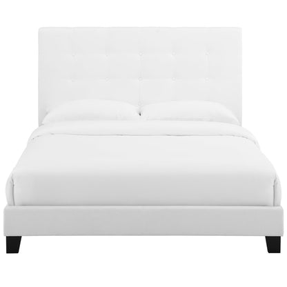 White tufted upholstered bed with tall headboard and low platform frame, dressed in white bedding.