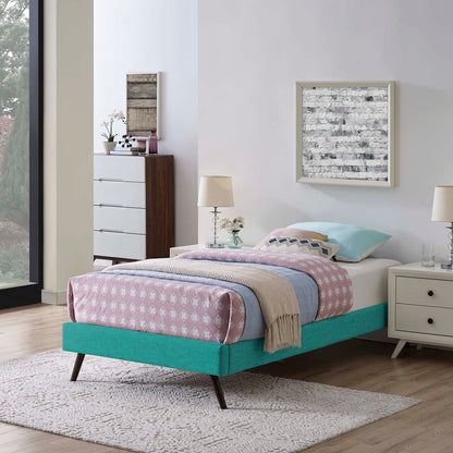 Teal fabric twin bed frame with round splayed legs, pink diamond quilt, light blue sheets, beige throw, white nightstands.