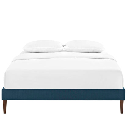 Low-profile navy blue upholstered platform bed with white bedding and two pillows, wooden tapered legs.