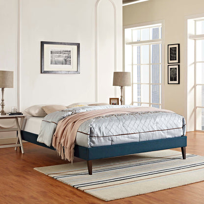 Blue fabric full bed frame with squared tapered legs in a chic modern bedroom, topped with a light gray quilted comforter and beige throw.