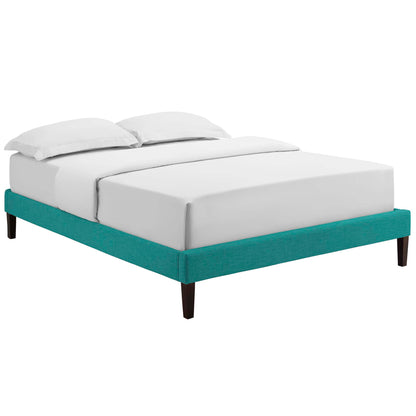 Teal upholstered bed frame with squared tapered dark wood legs, white sheets and two pillows.