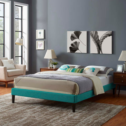 Teal upholstered platform bed with beige bedding, gray walls, botanical wall art, and wood nightstands with lamps.