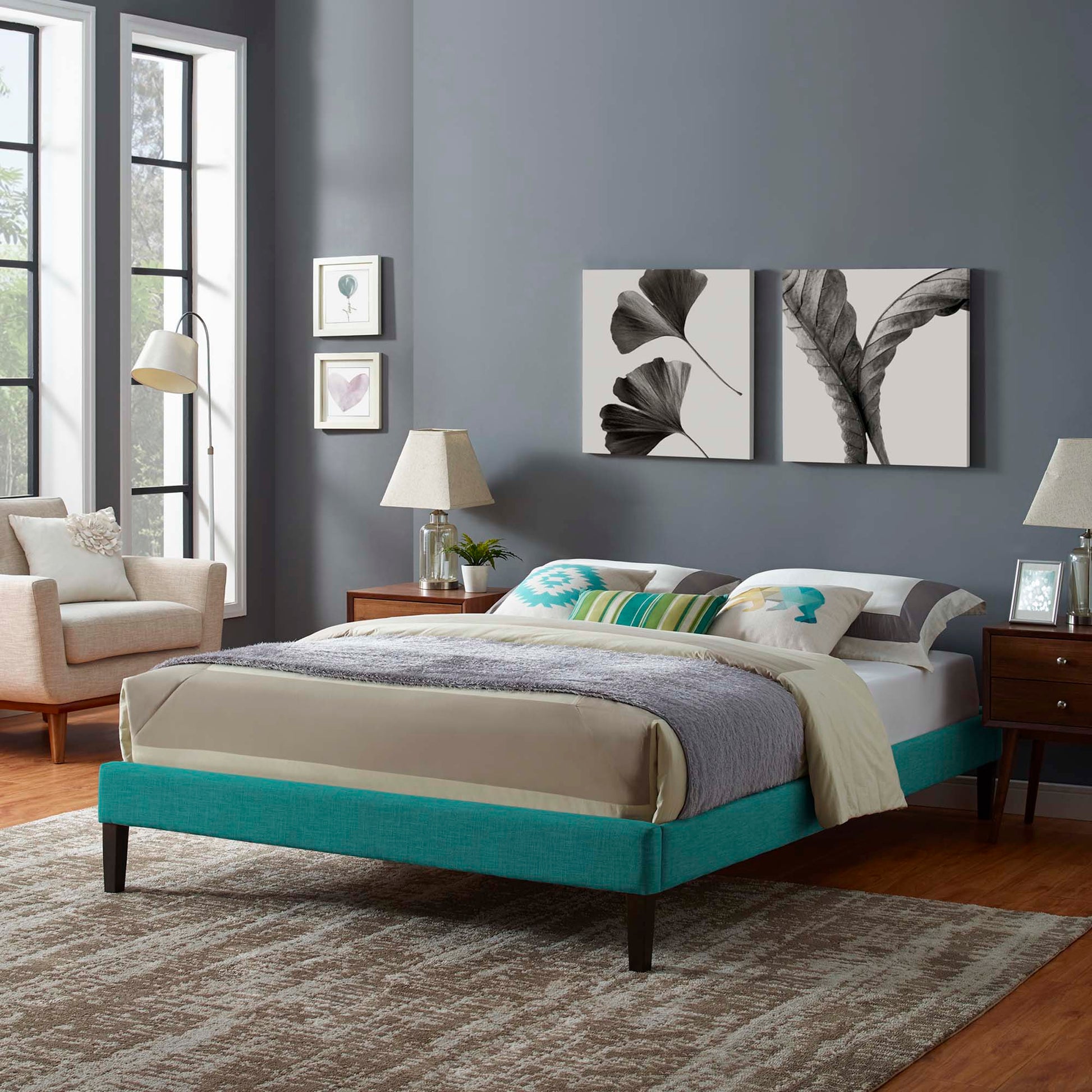 Teal fabric king bed frame with beige linens and gray throw, two dark wood nightstands, coastal modern bedroom.