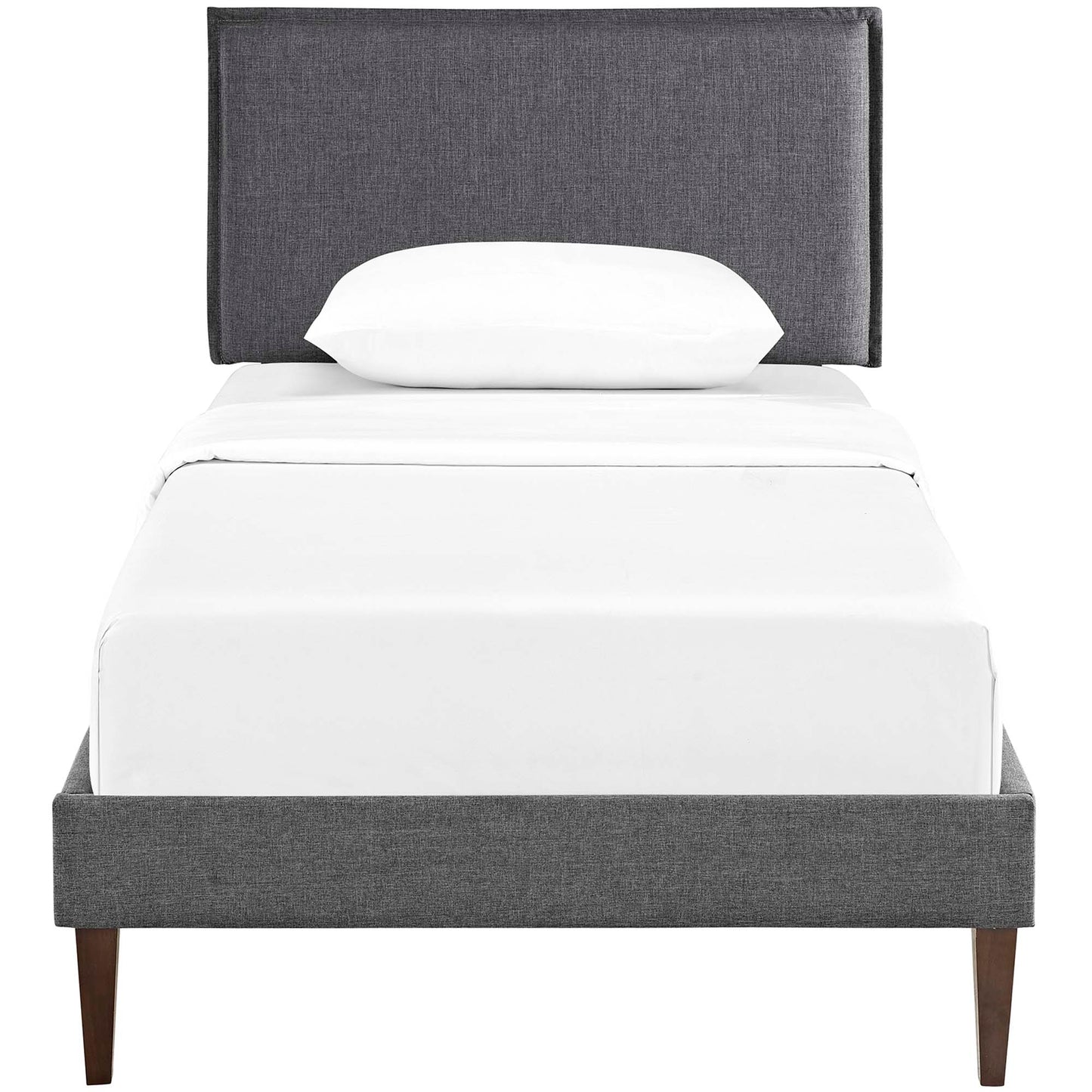 Gray upholstered platform bed with tall headboard, white sheets and pillow, tapered wood legs.