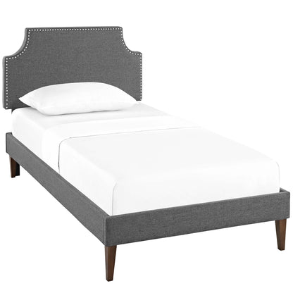 Gray upholstered twin platform bed with squared tapered legs, fabric frame, and white bedding.