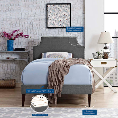 Grey fabric twin platform bed with squared tapered legs and LVL slats; blue bedding and cozy throw