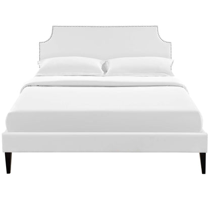 White upholstered bed with curved studded headboard, low footboard, and dark tapered legs.