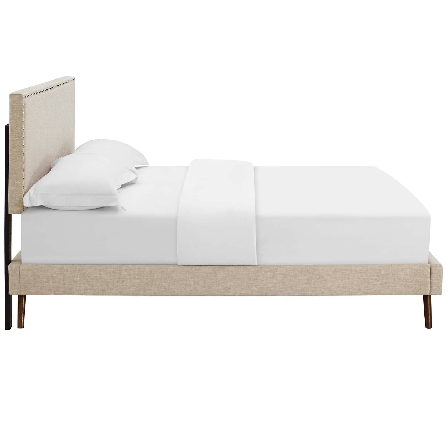 Beige fabric queen platform bed with a tall padded headboard and nailhead trim, round splayed legs, and white bedding.