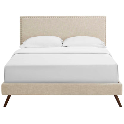 Beige upholstered platform bed with studded nailhead trim headboard, white bedding and round splayed legs.