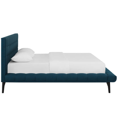 Blue upholstered platform bed with tufted tall headboard and low footboard, black tapered legs, white bedding.
