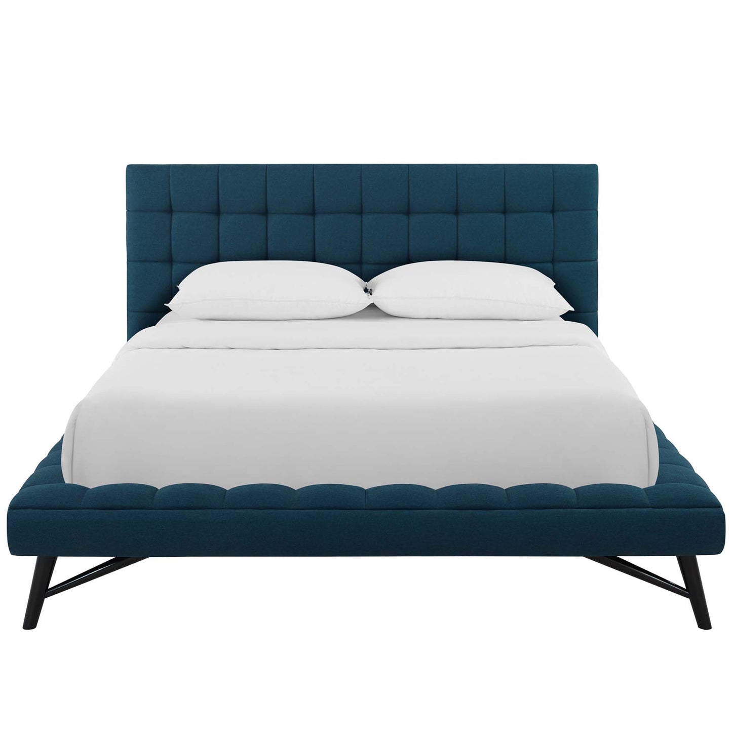 Blue tufted upholstered platform bed with low footboard, angled black metal legs, & white bedding.