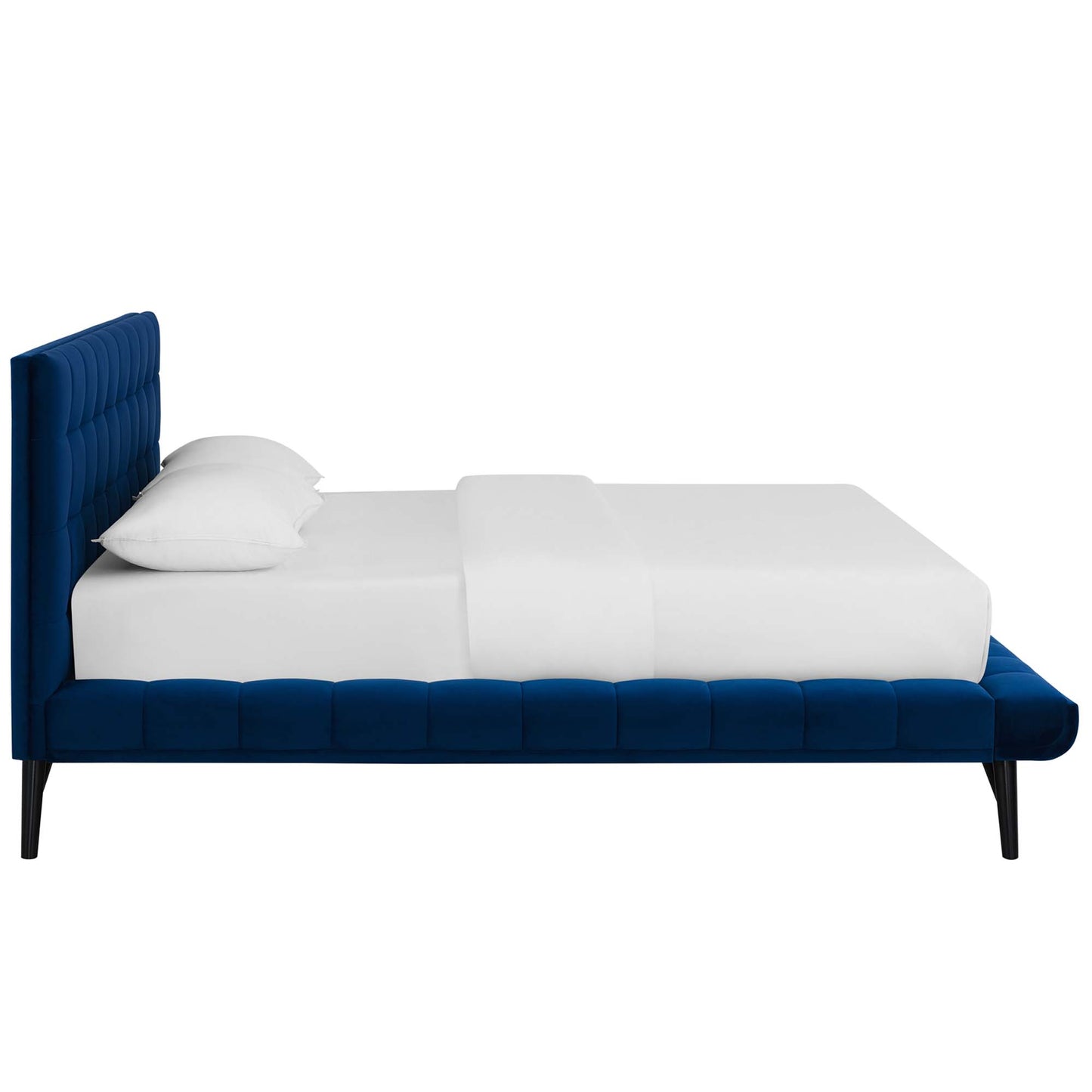 Navy blue velvet tufted platform bed with tall headboard, white sheets & pillows, black tapered legs.