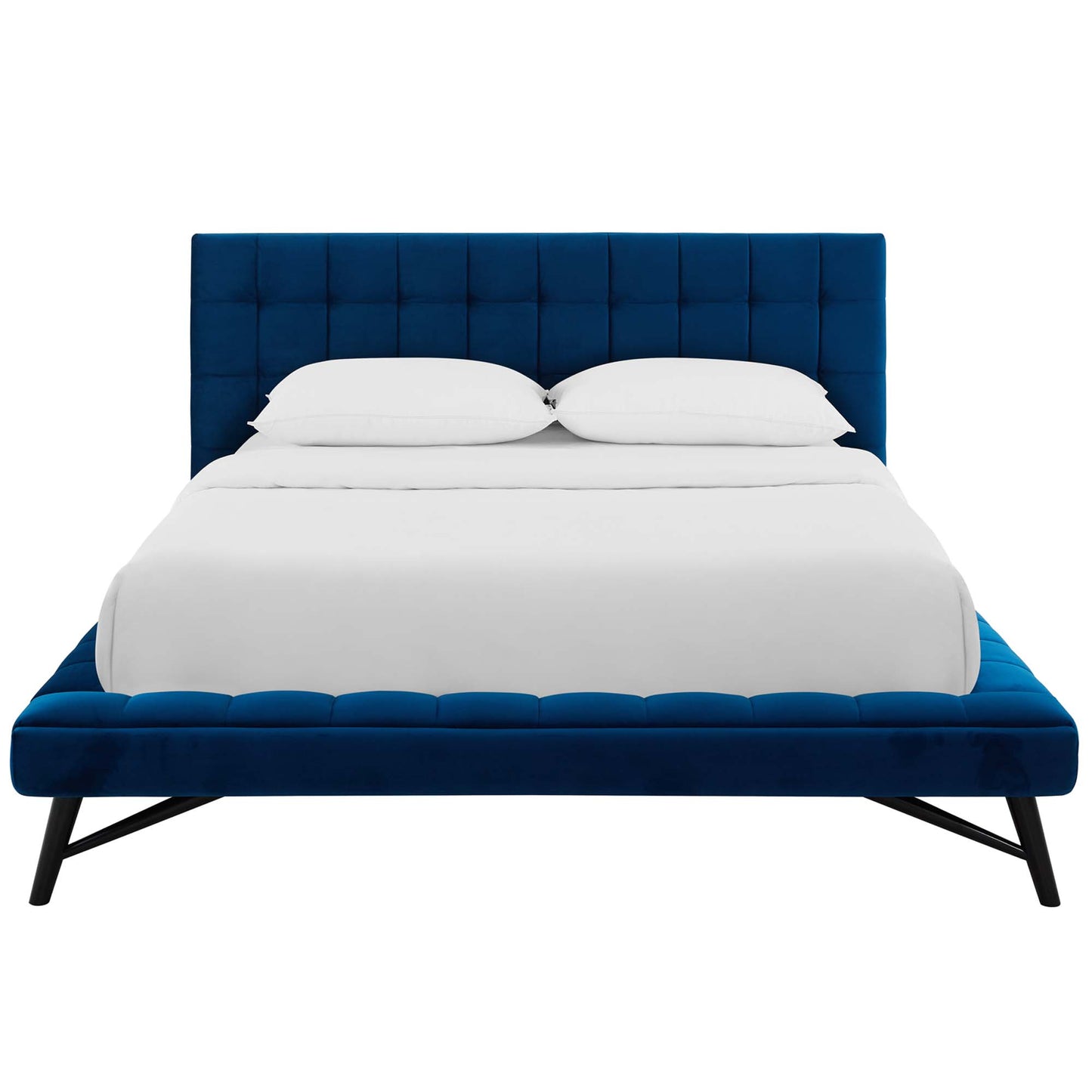 Navy blue tufted platform bed with tall padded headboard, low footboard, angled black legs, white bedding.