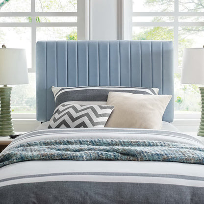 Soft blue velvet twin headboard with vertical channels, gray-blue bedding, chevron gray pillow, beige pillow, and textured throw.