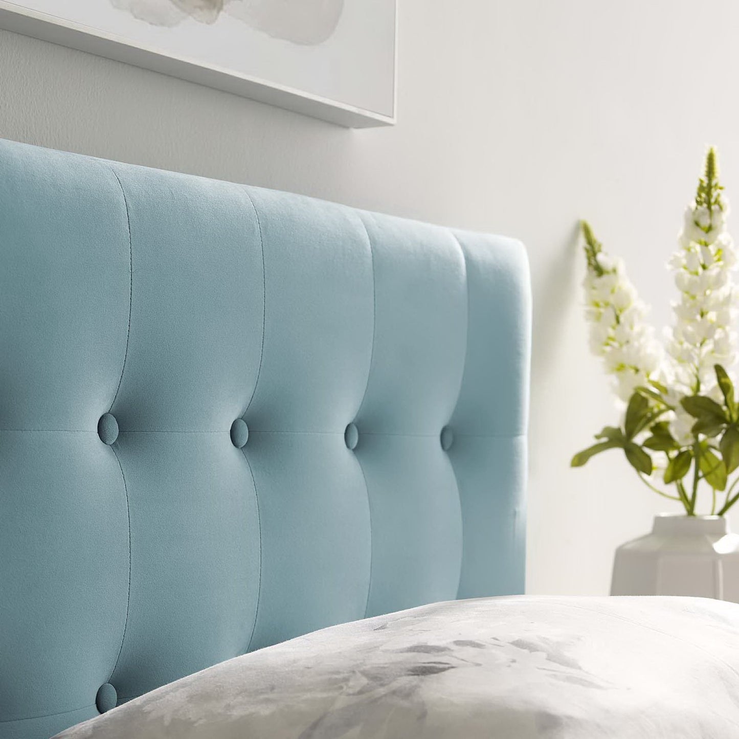 Light blue tufted upholstered bed headboard with button details in a modern bedroom.