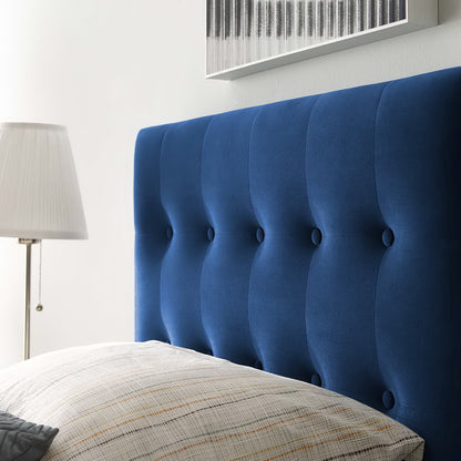 Navy blue tufted twin headboard with button accents in a bedroom, paired with light striped bedding and a white shade lamp.