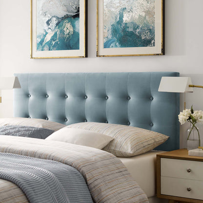 Blue tufted upholstered queen headboard with beige striped bedding and gold-framed abstract art above.