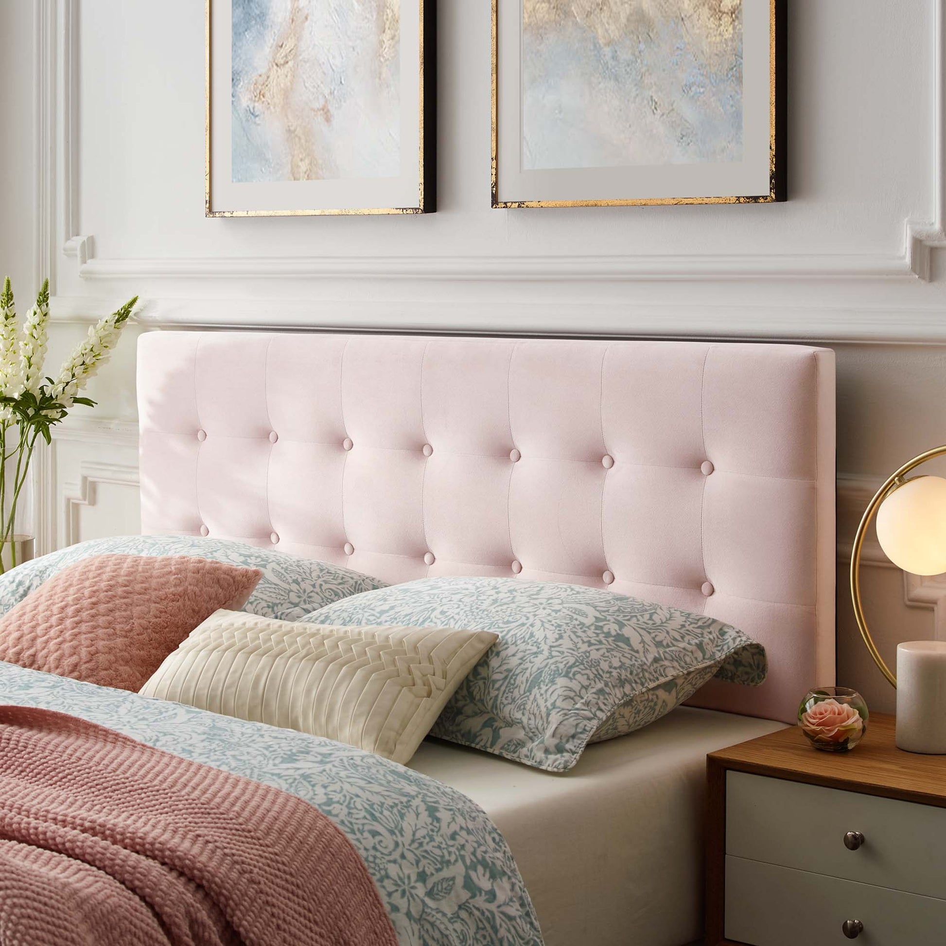 Soft pink tufted queen headboard with pastel damask bedding, beige and blue cushions, and a peach throw.