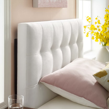 White tufted headboard with vertical channels; blush pink and white pillows on bed beside window and yellow flowers.