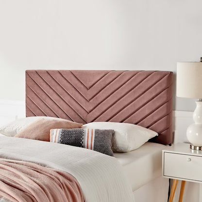 Dusty rose upholstered headboard with chevron stitch pattern, paired with white bedding and a striped throw.