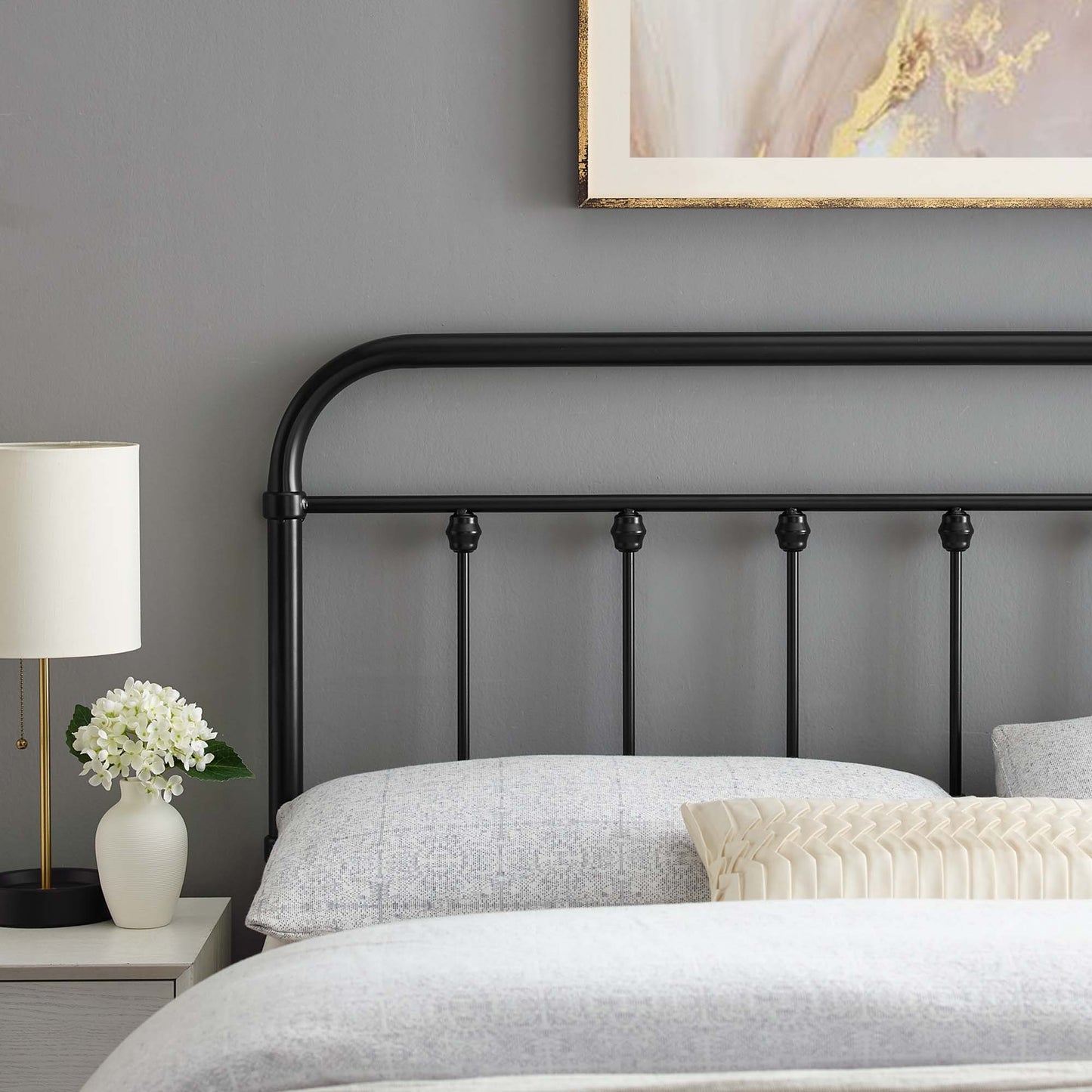 Black metal headboard with a curved top and slim vertical bars, gray bedding and a cream decorative pillow