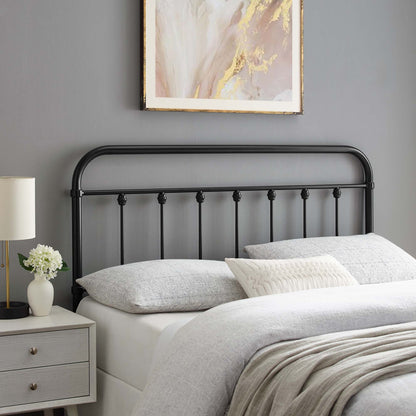 Black metal king headboard with rounded top rail and vertical spindles, gray bedding, beige throw, with gray nightstand and lamp.