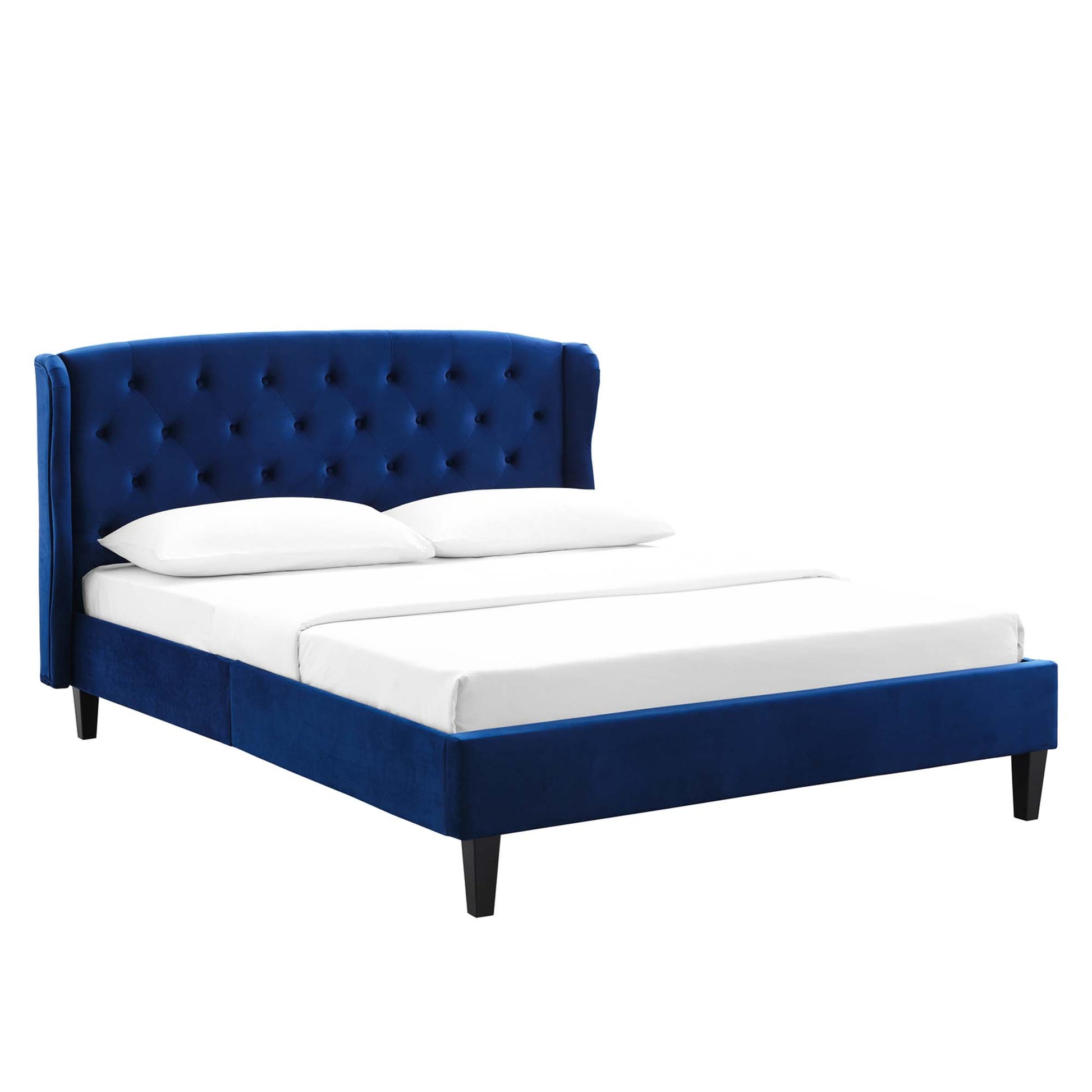 Navy blue velvet platform bed with tufted wingback headboard and dark tapered legs, dressed in white bedding.