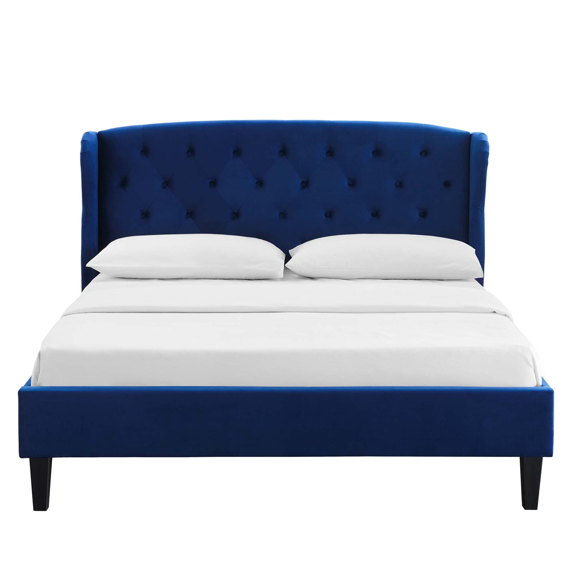 Navy blue upholstered bed with tufted headboard, low footboard, black tapered legs, white sheets and pillows.
