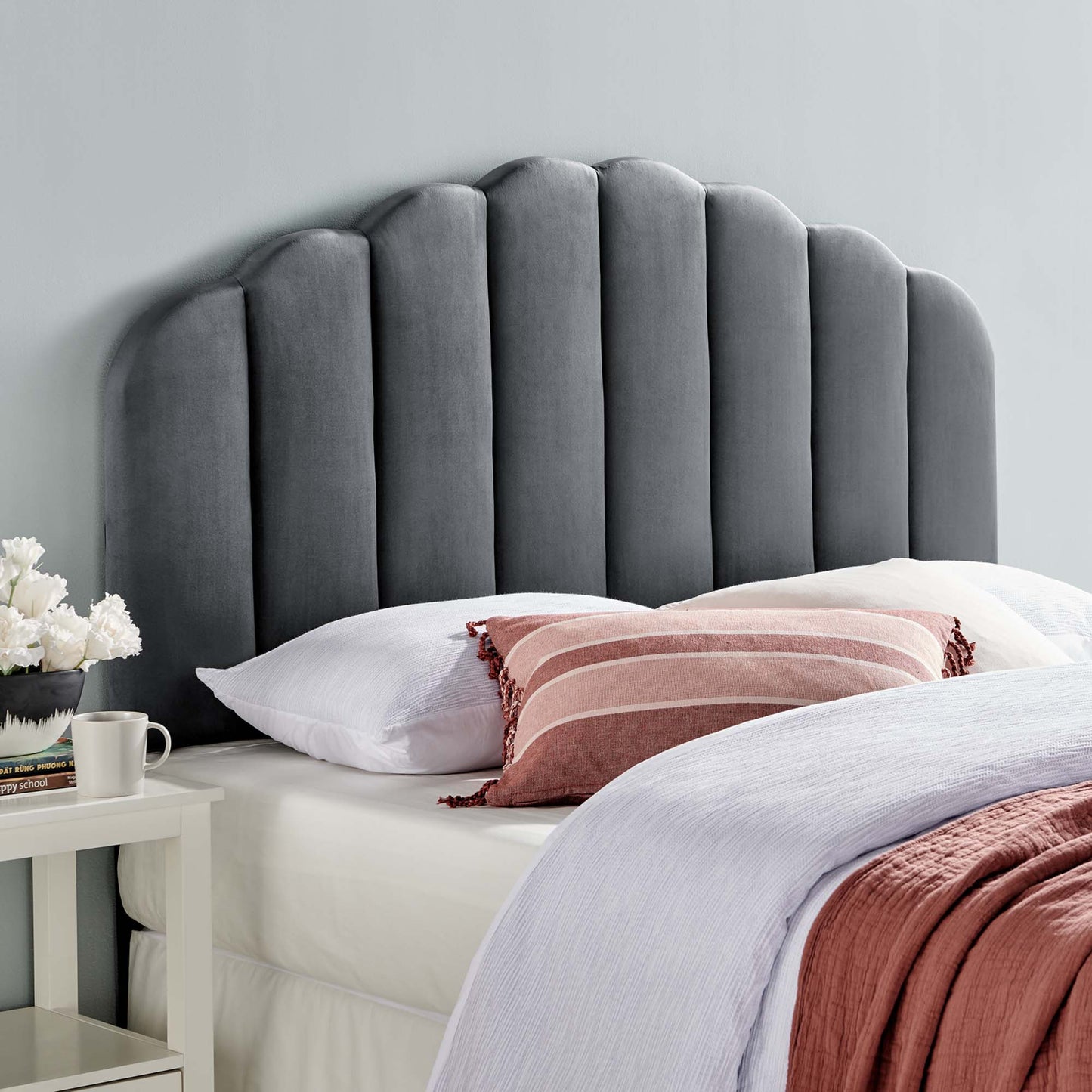 Gray velvet scalloped headboard, white bedding, pink striped lumbar pillow, lavender throw, white nightstand with flowers