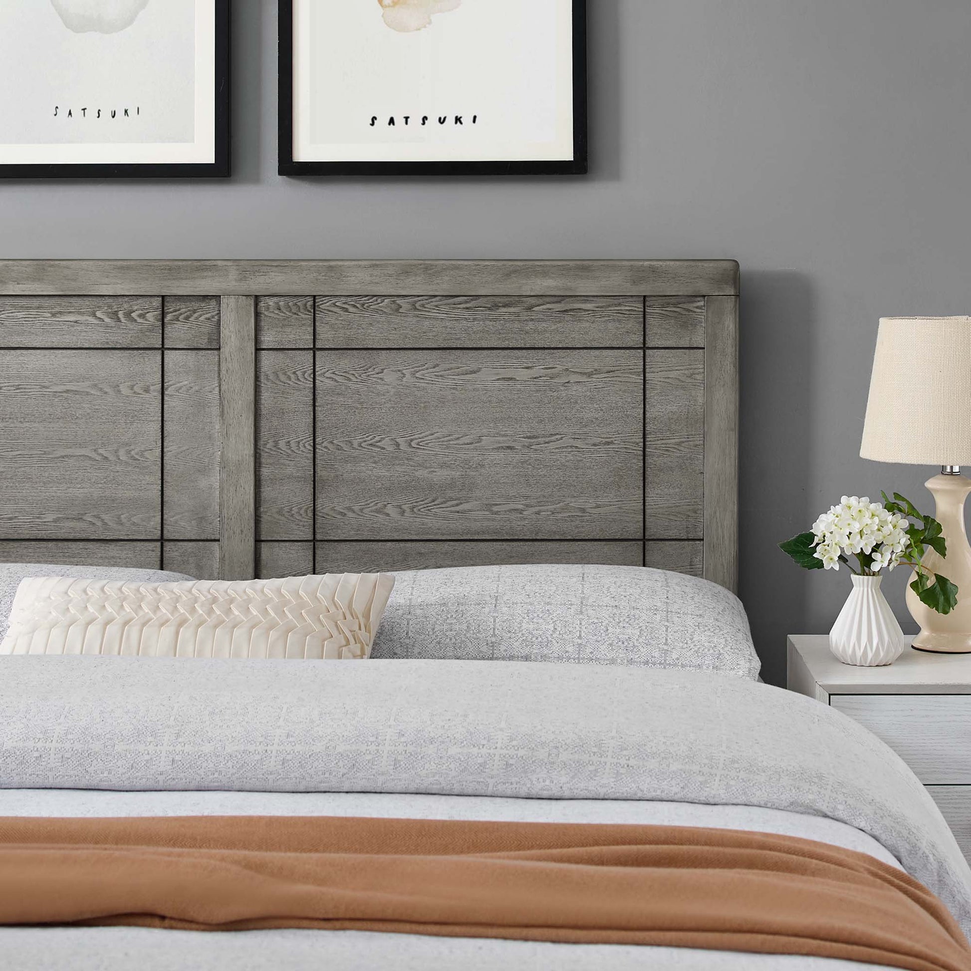 Weathered gray wood headboard with light-gray bedding, rust throw at foot, beige pleated pillow, white nightstand with lamp.