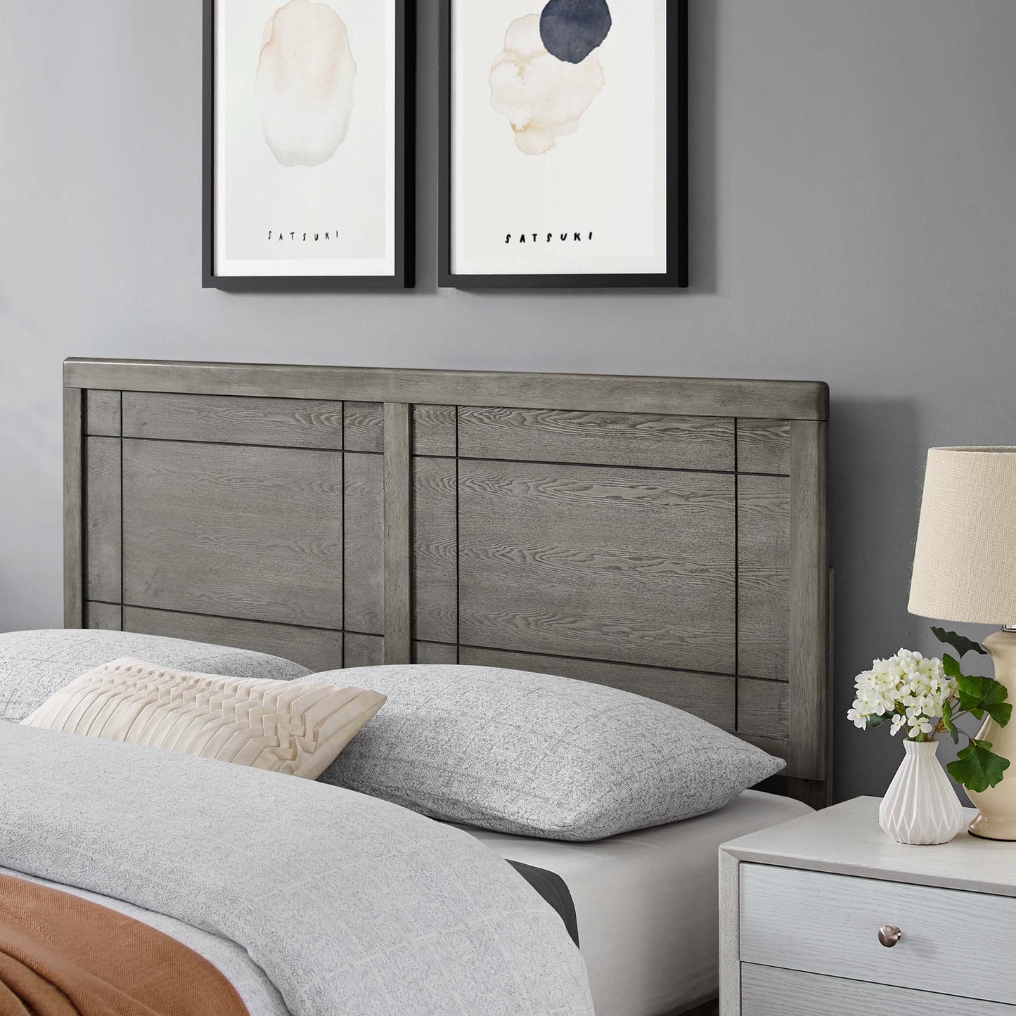 Weathered gray wood headboard with panel details, paired with gray bedding and beige pillow; rustic-modern bedroom.