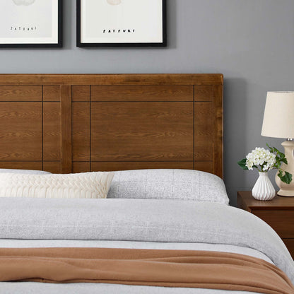 Brown wood King headboard with geometric panels, grey bedding, cream pleated pillow, rust throw; lamp and vase of white flowers.