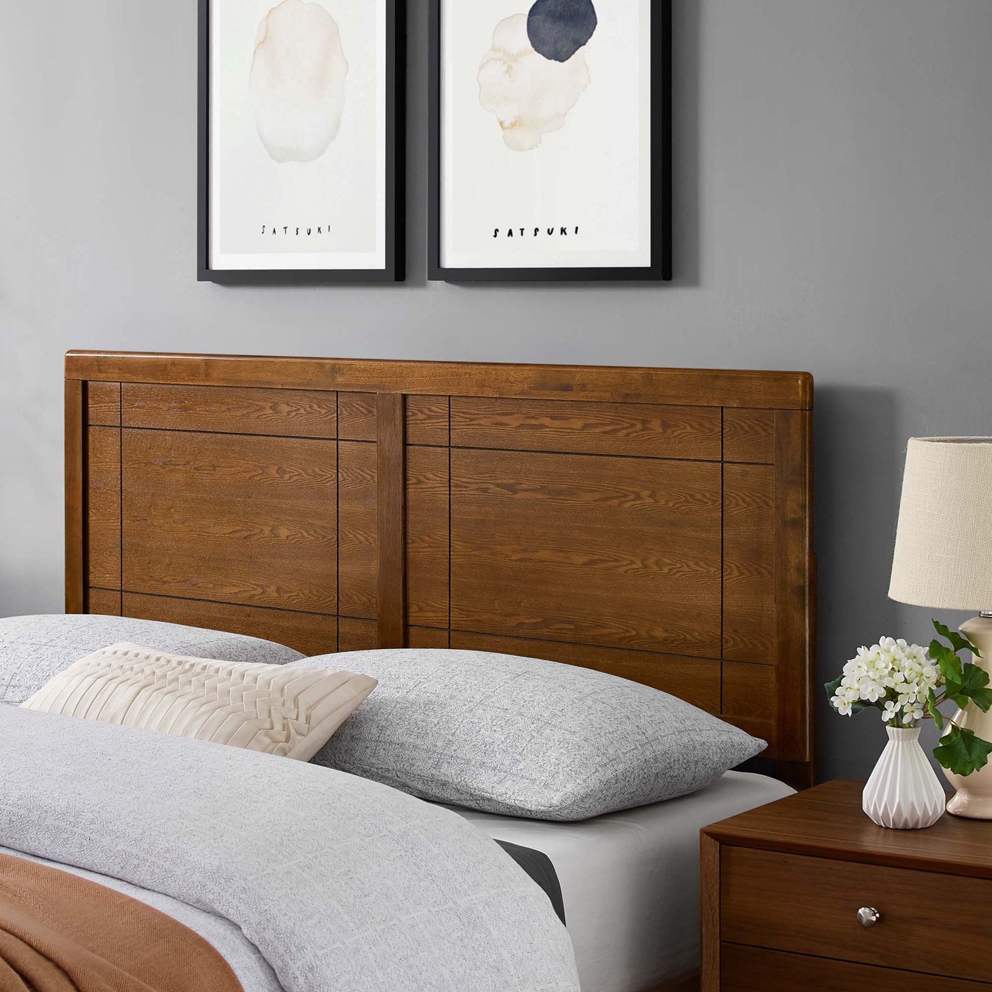 Walnut wood king headboard with a paneled design, set against gray walls with white bedding in a mid-century modern style.