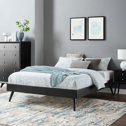 Black platform bed with tapered legs, blue floral bedding, gray walls, and abstract blue art above.