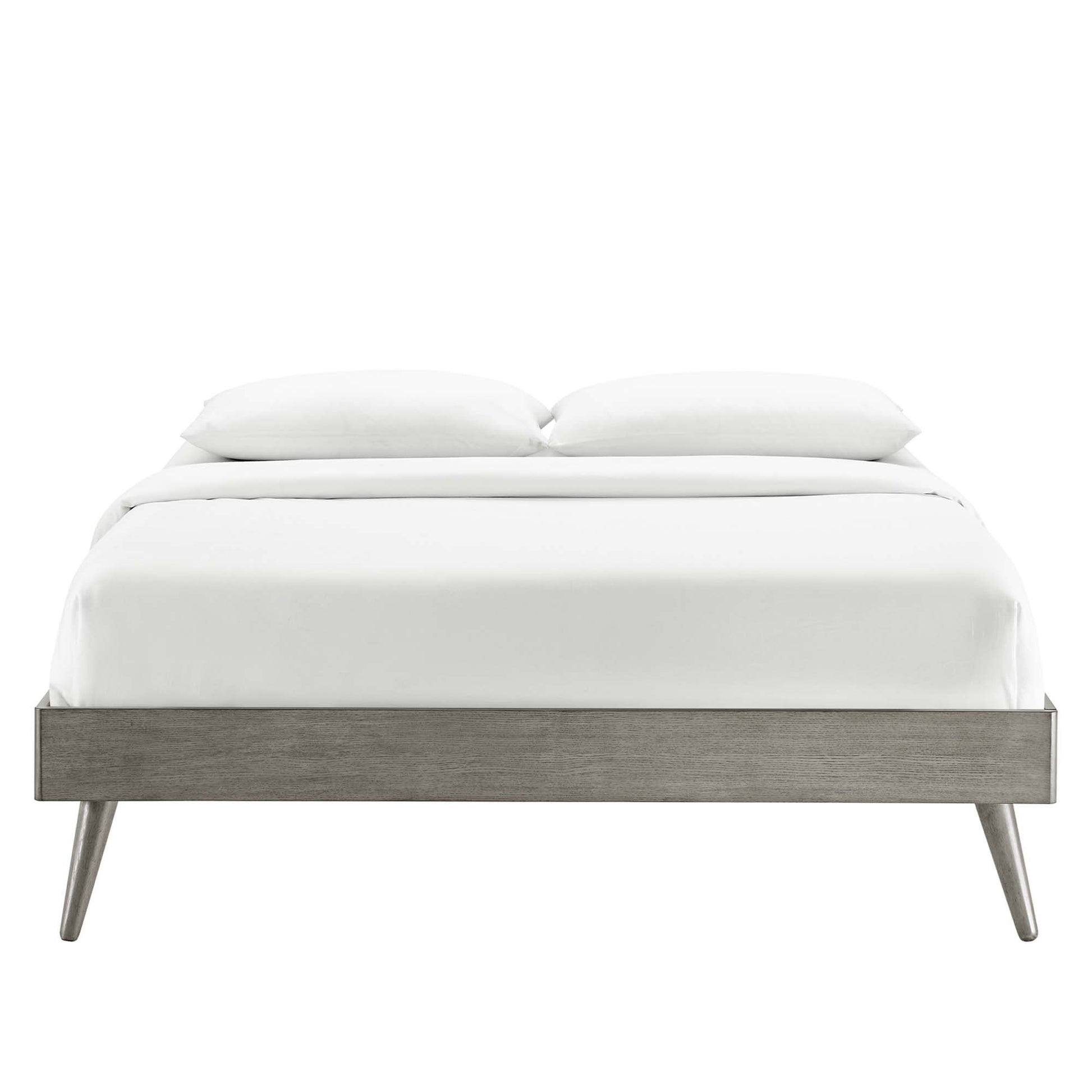 Gray wood platform bed frame with tapered legs in a mid-century modern design, dressed in white linens and two pillows.