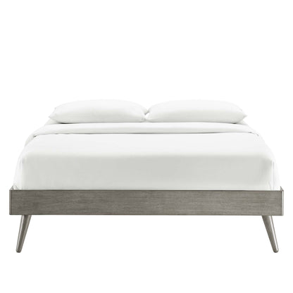 Gray wood platform bed frame with tapered legs in a mid-century modern design, dressed in white linens and two pillows.