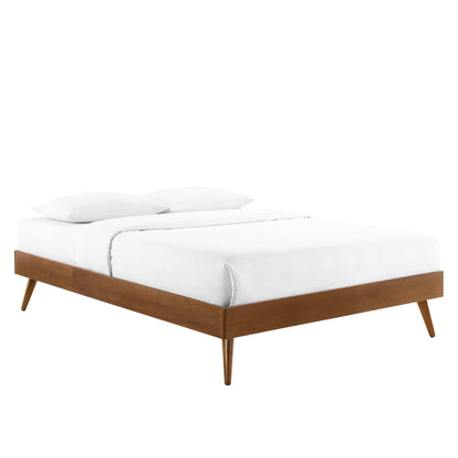 Walnut platform bed with tapered legs in mid-century style, dressed in white bedding with two pillows.
