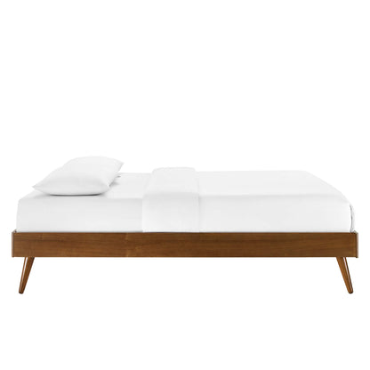 Walnut king platform bed frame with white linens and a single pillow, tapered legs.