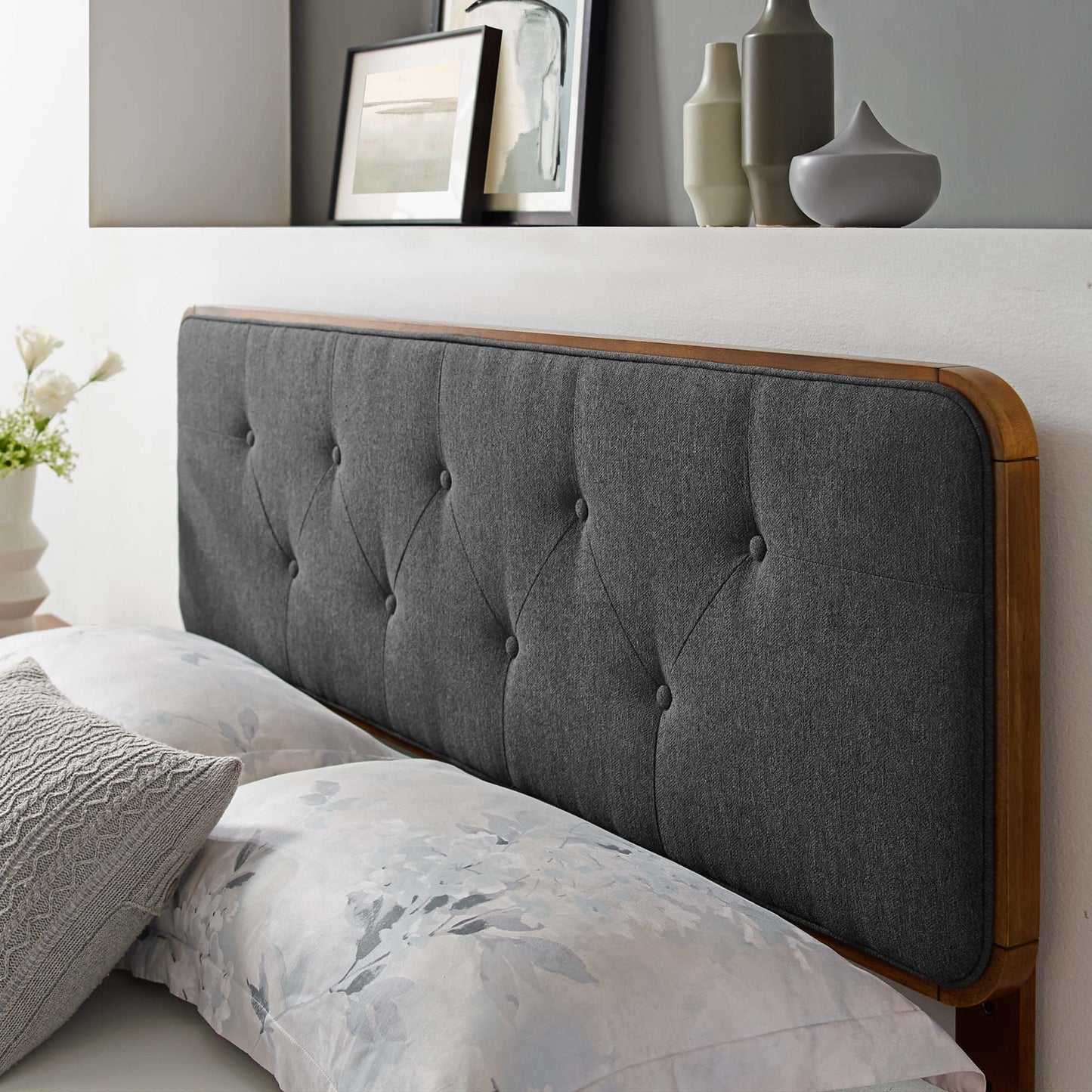 Black tufted fabric headboard with wooden frame and rounded edges, paired with floral bed linens.