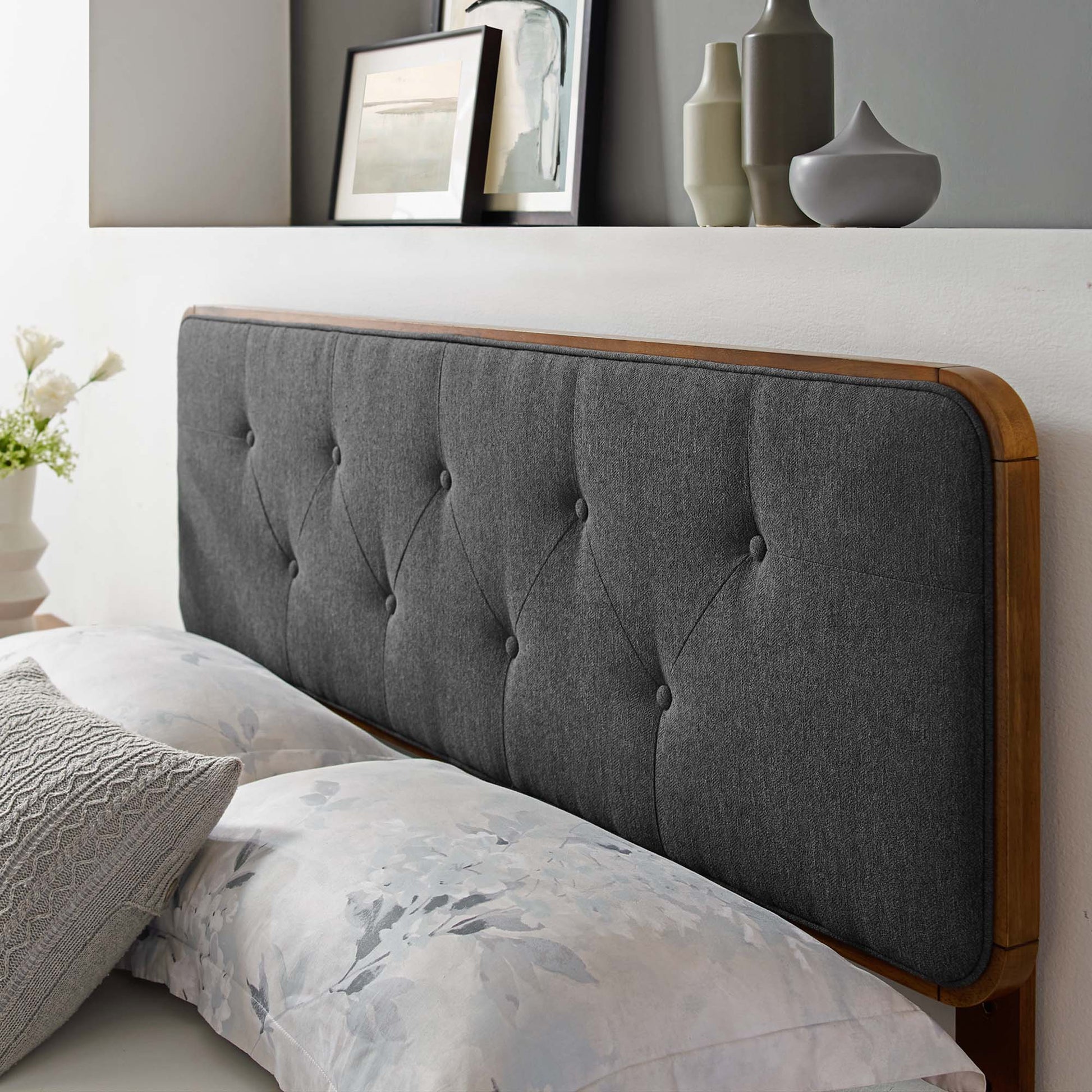 Black tufted fabric headboard with wooden frame and rounded edges, paired with floral bed linens.